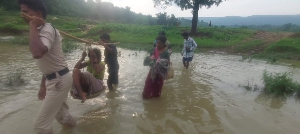 Image showing police officers carrying a stretcher with a pregnant woman across a hill in Raigarh.