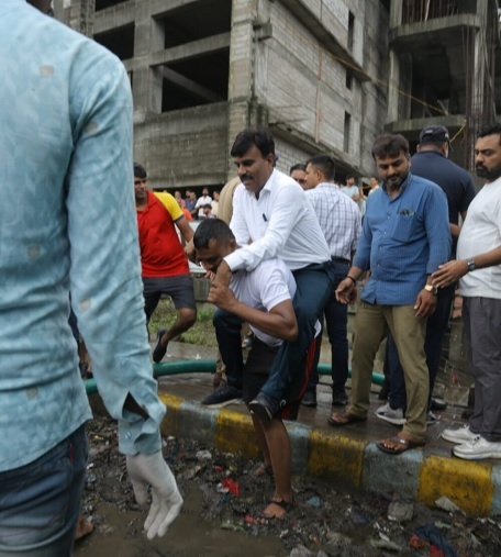 "Deputy Mayor Narendra Patil rides on a fire officer's shoulders to avoid mud during a flood inspection in Surat, Gujarat; the incident goes viral."
